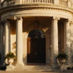 Fresh Prince mansion glowing with golden light and ornate columns with potted plants and lush greenery