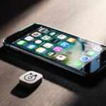 Sleek iPhone showing Liquid Glass design with dark wood background and innovative side light and alarm slider icon lying flat