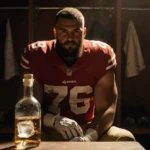 George Kittle sitting in locker room holding his injured ankle with tequila bottle on table and golden lighting showing deter