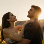 Hailee Steinfeld hugs Josh Allen on football field with golden sunset and teammates in background