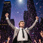 Harry Styles raising his arms with confetti swirling around him and neon lights illuminating Madison Square Garden stage