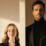 Two people stand face to face with dramatic height difference and elegant outfits under warm glamorous lighting