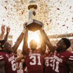 Hoosiers players lift championship trophy with cheering crimson and cream fans and sunset glow over IU Stadium