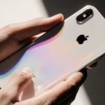 Hands holding iPhone Air with transparent back gleaming under soft natural light and subtle gradient screen.
