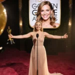 Jessie Buckley celebrating Golden Globe win with arms outstretched and Julia Roberts smiling on screen behind her