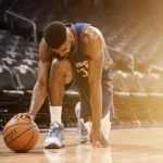 Jimmy Butler clutching his knee in pain with basketball nearby and empty arena seats behind