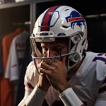 Josh Allen crying at locker with Bills helmet overhead and Broncos helmet visible through door