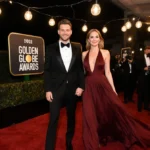 Julia Roberts and Danny Moder walk hand-in-hand on the red carpet with her crimson dress flowing behind them