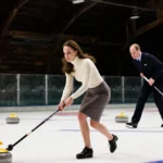 Kate Middleton sweeping a curling stone with Prince William gliding across the dimly lit ice