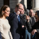 Kate Middleton and Prince William stand with stern faces near a street performer shouting about Prince Andrew and Jeffrey Eps
