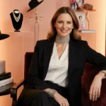 Kendra Scott posing confidently with sparkling choker necklace and designer hats from her collection