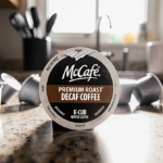 K-Cup pod displaying recall notice with torn label on cluttered kitchen counter and warm kitchen light