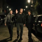 Kiefer Sutherland surrendering to ride-share drivers with cars parked at angles under flickering alley lights