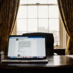 King Charles looking at laptop screen with embarrassing social media message visible on royal office desk