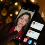 Kristy Scott watching TikTok on phone with blurred ex-partner and Christmas tree glow behind her
