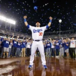 Kyle Tucker celebrates with arms raised and Dodgers fans cheering at Dodger Stadium with confetti falling