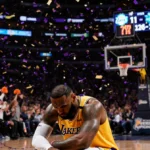 Lakers player slumps with head in hands while Hornets celebrate victory with confetti falling and scoreboard showing 135-117