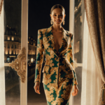 Lauren Sánchez Bezos smiles while stepping out of a Parisian evening with golden light and a vintage Versace gown.