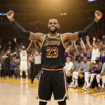 LeBron James celebrates on court with arms raised and Lakers bench cheering behind him