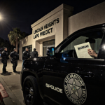 SWAT team gathering around black SUV with Lincoln Heights precinct lit by flickering streetlight and warrant
