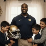 Marcus Freeman stands with his six children near football trophies and family photos with natural light streaming through the