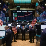 Traders shouting at monitors with Bitcoin price flashing red and American flag showing market volatility