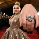 Miley Cyrus posing on red carpet with sequined gown and engagement ring flashing under golden lights