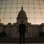 Mayor Jacob Frey stands on Minneapolis City Hall steps with federal troops visible in background