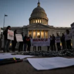 Protesters hold signs at Minnesota courthouse with scattered papers and broken chains on ground