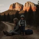 Mother and son hiking on Shafer Trail with red rock formations and scattered gear showing lost hikers