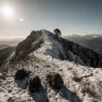 Rugged trailhead looms with snow-covered backpacks trekking poles and a faint distant trail under a grey-blue sky
