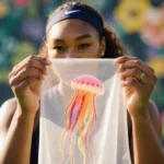 Naomi Osaka holding a translucent jellyfish‑inspired fabric swatch with warm glow and floral background