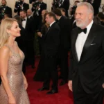 Nikki Glaser approaches Rob Reiner on the Golden Globes red carpet with celebrities mingling behind them