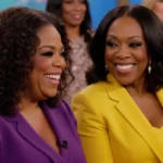 Oprah Winfrey and Whoopi Goldberg sharing warm conversation on The View with vibrant outfits and hosts visible behind them