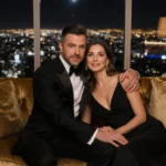 Paul Mescal and Gracie Abrams embracing on gold couch with city skyline glowing through windows behind them