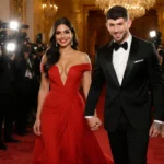 Priyanka Chopra Jonas and Nick Jonas walking hand-in-hand on red carpet with her red gown and his black tuxedo