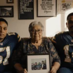 Penina Nacua sits with family surrounded by football jerseys and photos with framed picture on her lap