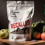 Bag of organic chia seeds exposes recalled label with red text on a rustic wooden board surrounded by fruits and vegetables.