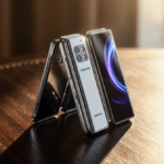 Samsung Galaxy Z TriFold smartphone unfolding with three flexible OLED displays on a dark wood desk and luxury golden glow