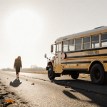 Grieving mother walking away from abandoned school bus with fading yellow paint and long shadows