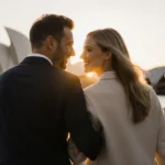 Scooter Braun and Sydney Sweeney walking hand in hand along Sydney harbor with Opera House in background at sunset