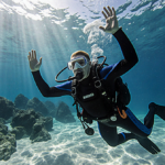 Scuba diver panicking underwater with arms raised and face contorted while waves lapping at feet near rocky shore