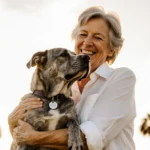 Elderly woman hugging senior dog with microchip tag visible on collar and Florida palm trees behind