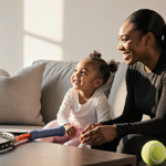 Serena Williams sits on couch with daughter Adira playing beside her and tennis racket on table light highlighting their bond