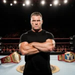 Shane McMahon standing confidently in the center of a luxurious wrestling ring with gleaming gold championship belts nearby.