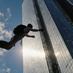 Skydiver soaring through World Tower hotel with glass façade reflecting sunlight and blue sky with wispy clouds