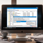 Computer desktop cluttered with papers and coffee cups showing error messages and Task Manager showing slow PC frustration