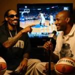 Snoop Dogg talking animatedly next to Reggie Miller with basketballs and microphones at their feet