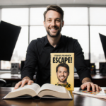 Stephen Fishbach standing in front of desk with two open books titled Escape! and Survivor and dual faces behind office set.