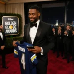 Sterling K. Brown walking red carpet with Golden Globes logo and Los Angeles city lights behind him